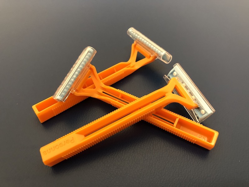 Three orange disposable razors